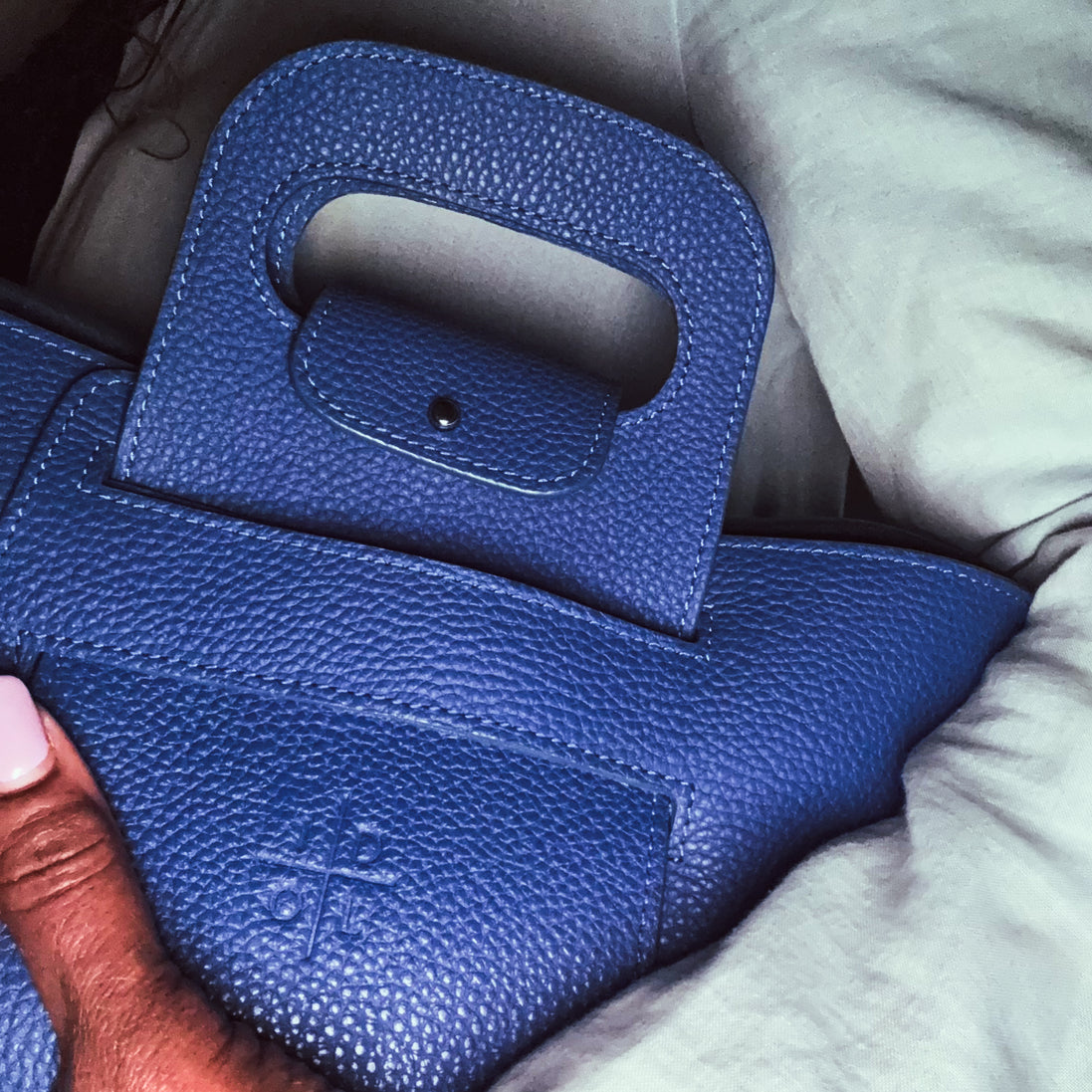 Close-up of a blue textured handbag held by a person with a blurred background